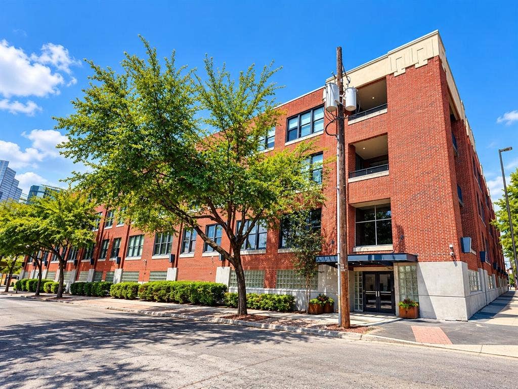 2502 Live Oak Street, #110, Dallas, TX 75204 Multi-story red brick exterior featuring large industrial-style windows, recessed balconies, glass block accents, and a covered entryway