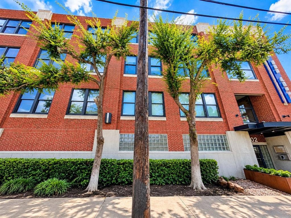 2502 Live Oak Street, #110, Dallas, TX 75204 Red brick exterior featuring multi-pane windows, concrete masonry accents, and decorative glass block detailing
