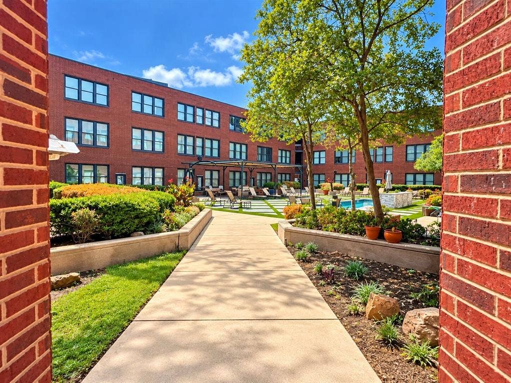 2502 Live Oak Street, #110, Dallas, TX 75204 Courtyard featuring a swimming pool, paved walkway, brick facade architecture, and manicured landscaping