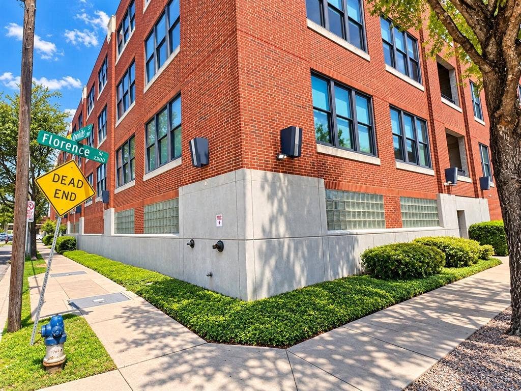 2502 Live Oak Street, #110, Dallas, TX 75204 Multi-story red brick exterior featuring a concrete base, glass block masonry, and grid-pattern window groupings