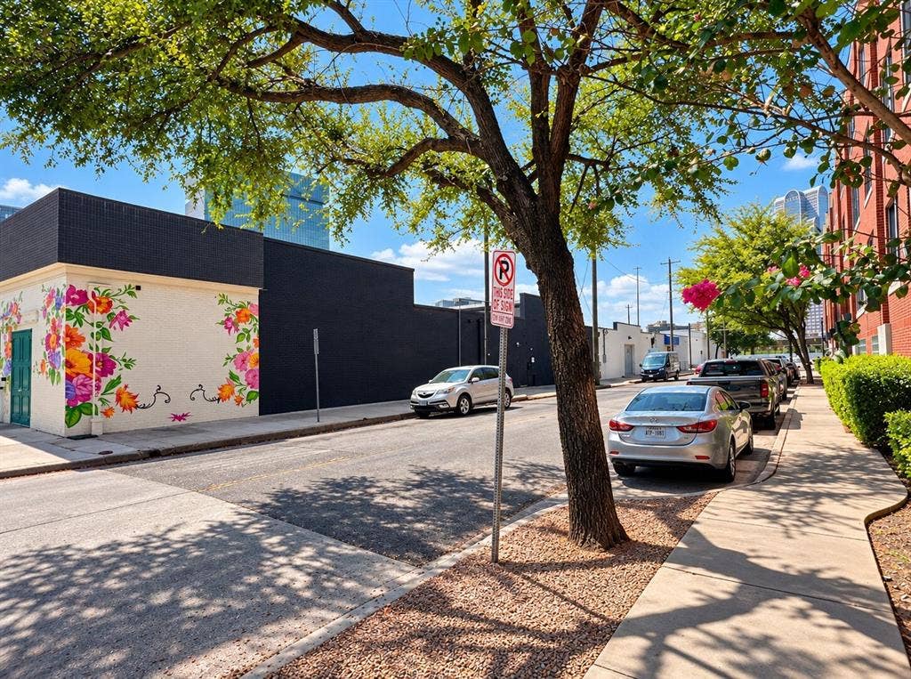 2502 Live Oak Street, #110, Dallas, TX 75204 Exterior facade featuring a matte black finish and a prominent floral mural, situated along a paved sidewalk with mature trees