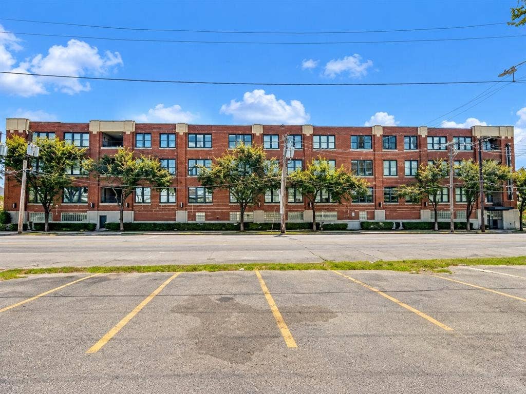 2502 Live Oak Street, #110, Dallas, TX 75204 Four-story brick exterior featuring a multi-pane window grid, stone-capped roofline, and ground-level glass block accents