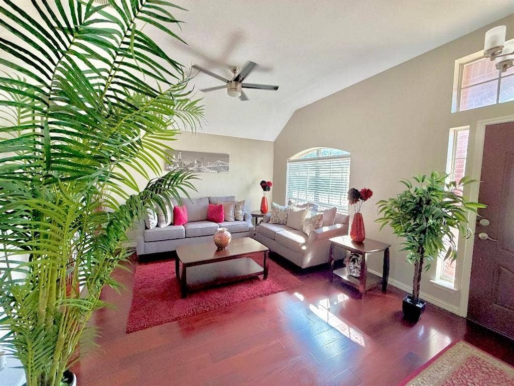Vaulted ceilings featuring a central ceiling fan, wood-finish flooring, and an arched window with blinds