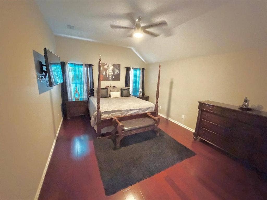 Vaulted ceilings, wood-finish flooring, and a ceiling-mounted light fixture with a fan