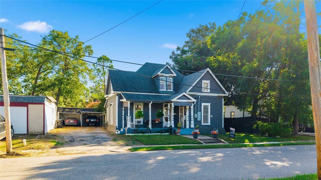 2309 Jones Street, Greenville, TX 75401 Two-story residence featuring a covered front porch, decorative gable accents, shingled roofing, and a detached carport structure