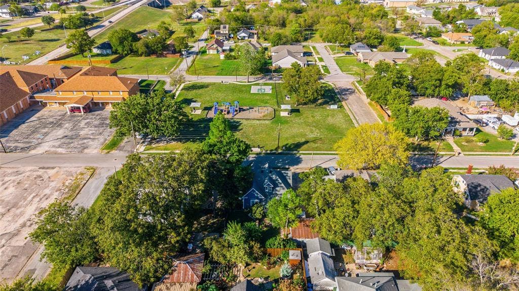 2309 Jones Street, Greenville, TX 75401 Aerial perspective of a residential lot featuring mature trees, established landscaping, and a fenced yard perimeter