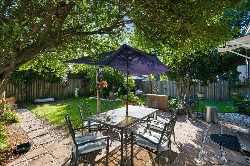 2309 Jones Street, Greenville, TX 75401 Backyard featuring a paved patio, manicured lawn, wood fencing, stone pathway, and mature trees