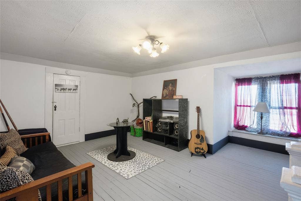 2309 Jones Street, Greenville, TX 75401 Painted wood-plank flooring, recessed window seat, five-light multi-directional ceiling fixture, and a solid-panel door with vintage hardware