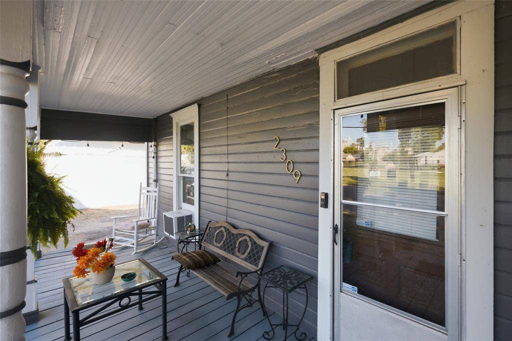 2309 Jones Street, Greenville, TX 75401 Covered front porch featuring wood-plank flooring, horizontal lap siding, and a transom window above the main entryway