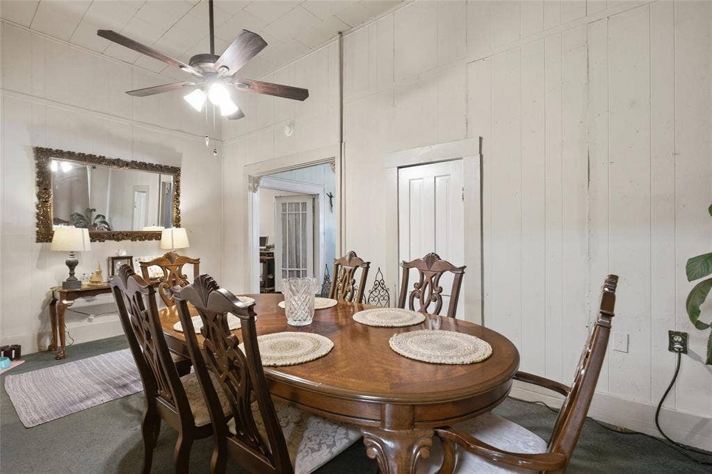 2309 Jones Street, Greenville, TX 75401 High-ceilinged room featuring vertical wood-plank walls and a multi-blade ceiling fan with integrated lighting