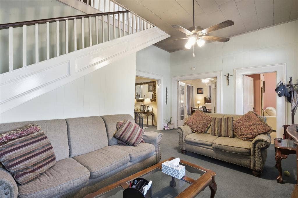 2309 Jones Street, Greenville, TX 75401 Staircase featuring a white balustrade with a stained wood handrail and recessed paneling, high ceilings, ceiling-mounted fan with integrated lighting, and crown molding