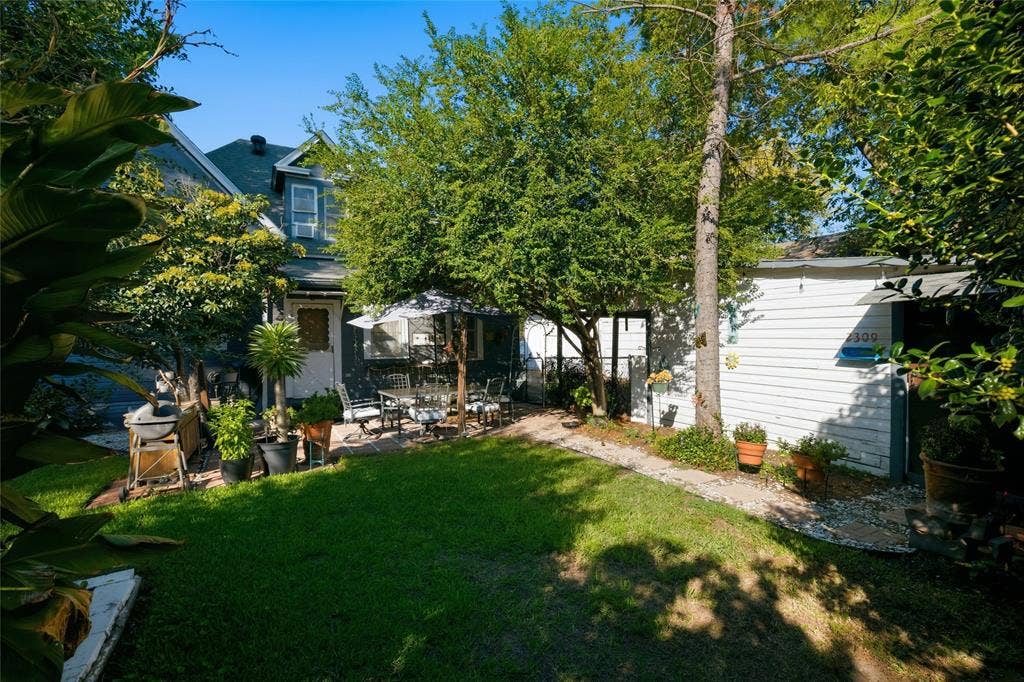 2309 Jones Street, Greenville, TX 75401 Enclosed backyard featuring a paver patio, mature trees, and a detached white-sided structure