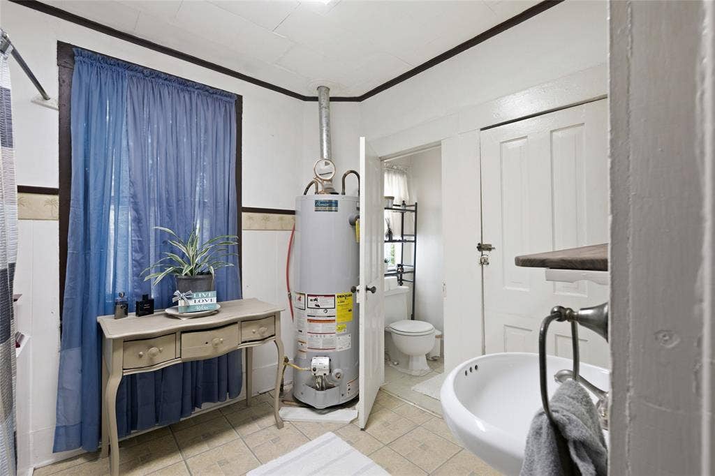 2309 Jones Street, Greenville, TX 75401 Wall-mounted sink with a metal hardware finish, tile flooring, and integrated water heating unit