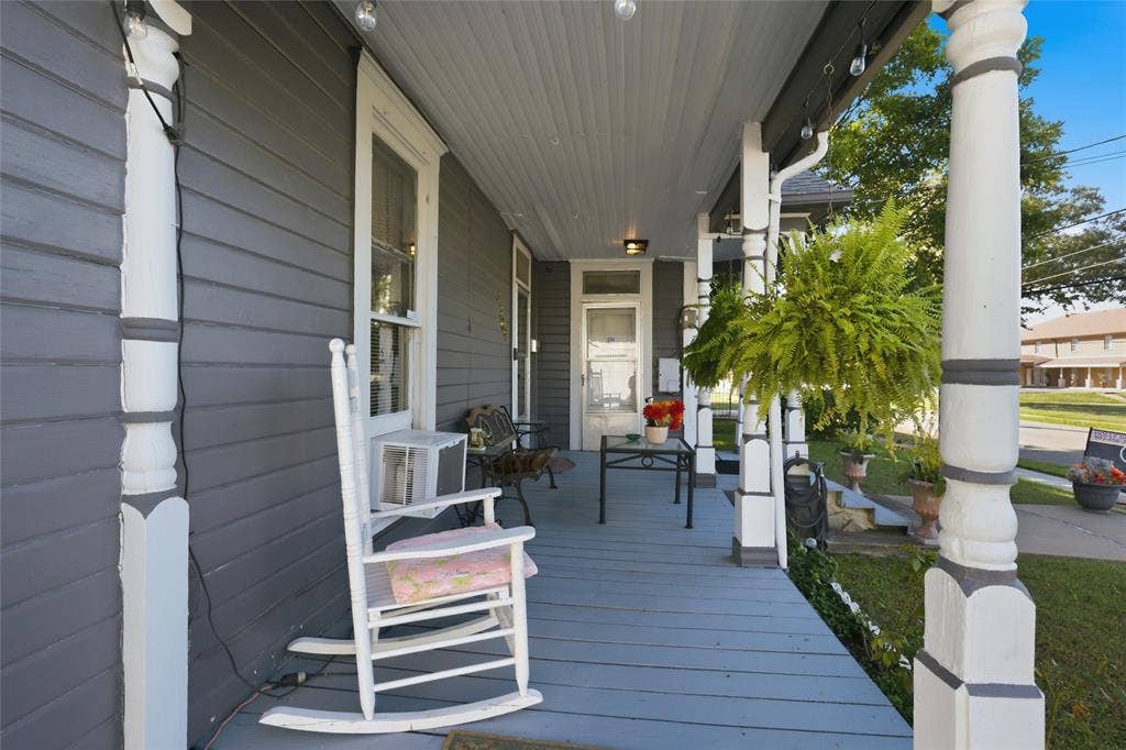 2309 Jones Street, Greenville, TX 75401 Covered porch featuring dark horizontal siding, decorative white columns, and painted wood-plank flooring