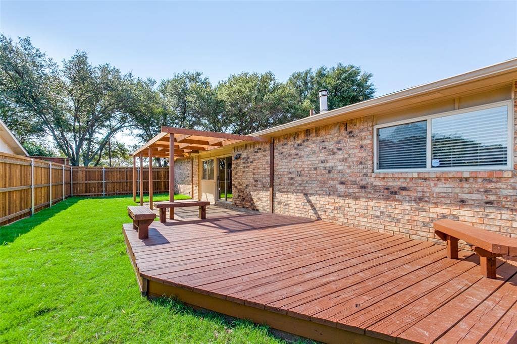 929 Arbor Downs Drive, Plano, TX 75023 Backyard featuring a multi-level wood deck, built-in wooden bench seating, a wood-frame pergola, brick exterior siding, and a wooden privacy fence