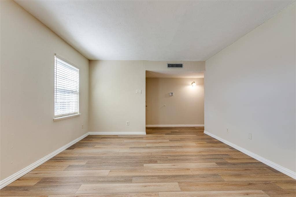 929 Arbor Downs Drive, Plano, TX 75023 Neutral-toned interior space featuring wood-finish flooring, a single window with horizontal blinds, and wall-mounted lighting