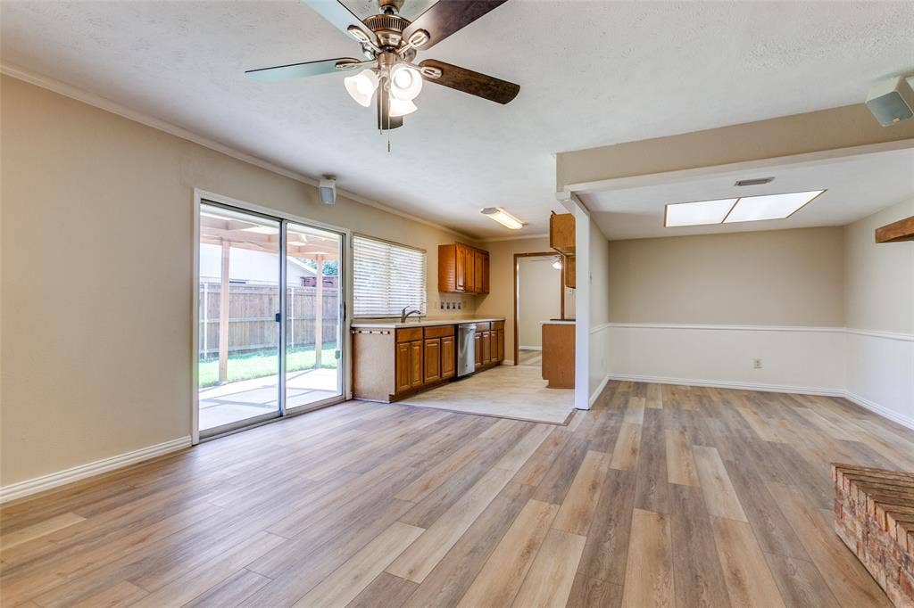 929 Arbor Downs Drive, Plano, TX 75023 Wood-finish flooring, sliding glass patio door, wooden cabinetry, recessed and ceiling-mounted lighting, and a brick-accented fireplace feature