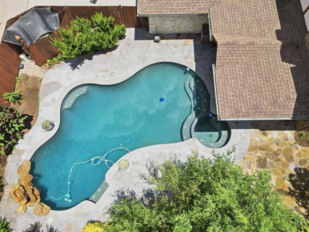 1509 Aylesbury Lane, Plano, TX 75075 Custom freeform pool featuring a built-in spa, stone hardscaping, rock water feature, and flagstone patio