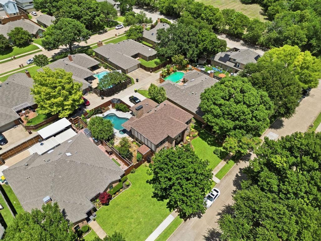 1509 Aylesbury Lane, Plano, TX 75075 Aerial perspective of a multi-structure property featuring a swimming pool, multiple pitched shingle rooflines, mature trees, and landscaped lawn areas
