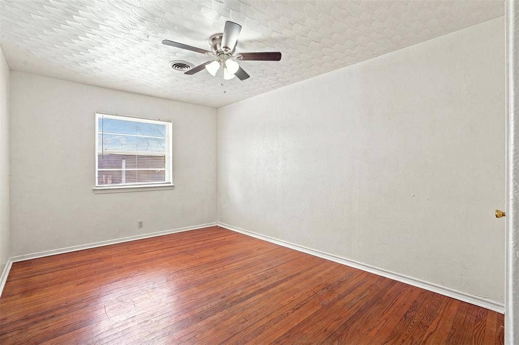 Room featuring wood-finish flooring, a ceiling fan with integrated lighting, a window with horizontal blinds, white baseboards, and a neutral wall color