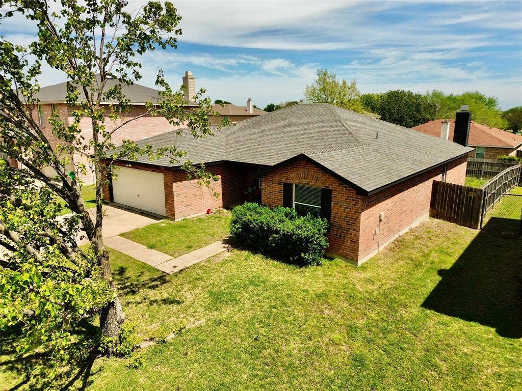 Ranch-style home featuring roof with shingles, brick siding, a garage, and a chimney