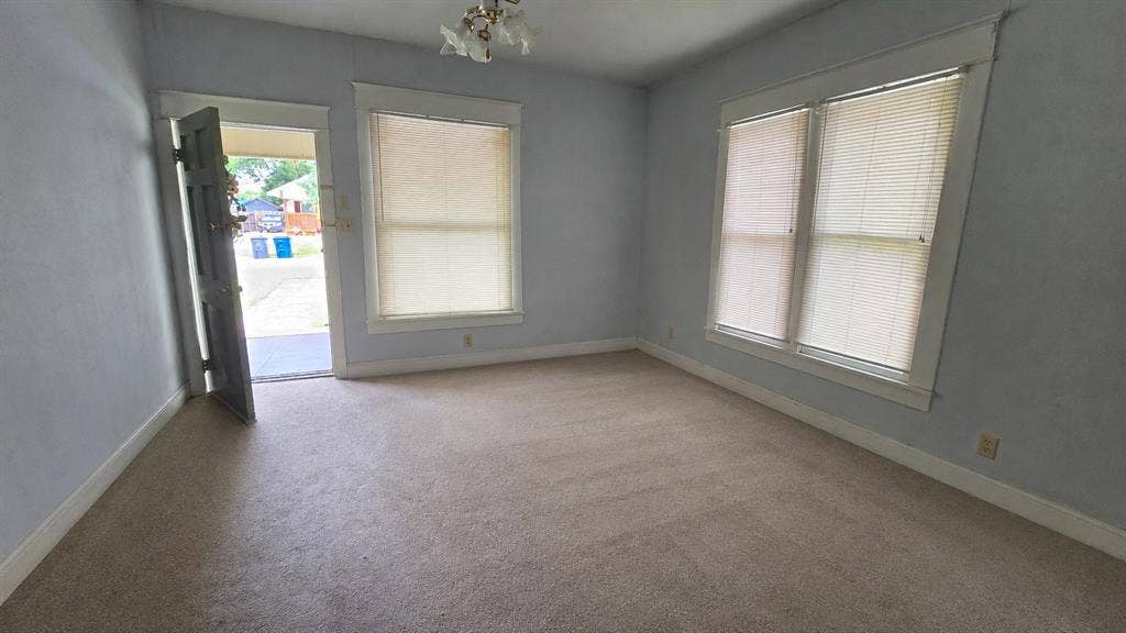 922 Hollywood Avenue, Dallas, TX 75208 Interior space featuring carpeted flooring, multiple windows with neutral blinds, and an exterior door with architectural trim