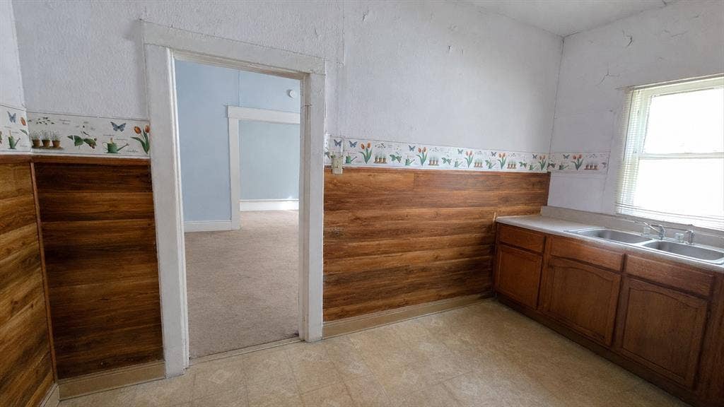 922 Hollywood Avenue, Dallas, TX 75208 Interior featuring wood-finish wall paneling, floral wall border, cabinetry with integrated double-basin sink, and natural light via a single window