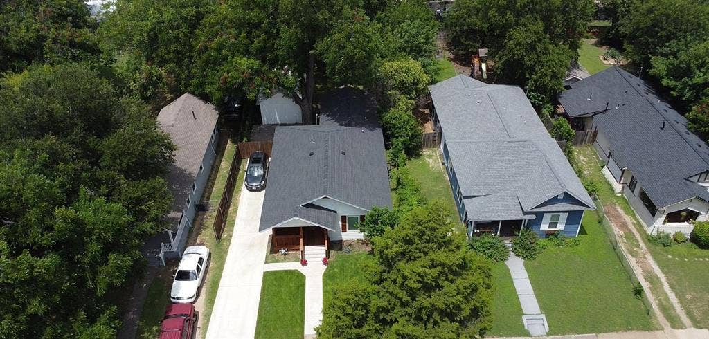 922 Hollywood Avenue, Dallas, TX 75208 Aerial perspective of a single-story residence featuring a shingled roof, a covered front porch, a concrete driveway, and established mature trees