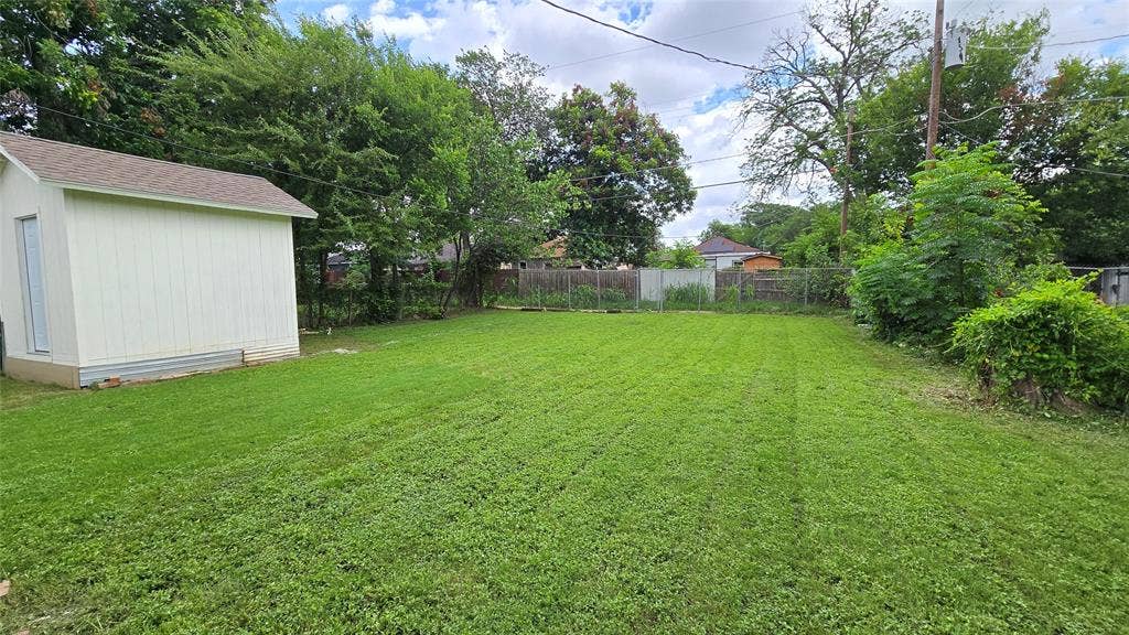 922 Hollywood Avenue, Dallas, TX 75208 Expansive backyard featuring a level lawn, detached storage shed, perimeter fencing, and mature trees
