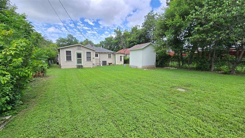 922 Hollywood Avenue, Dallas, TX 75208 Expansive backyard featuring a level grass lawn, detached storage structure, and mature perimeter trees