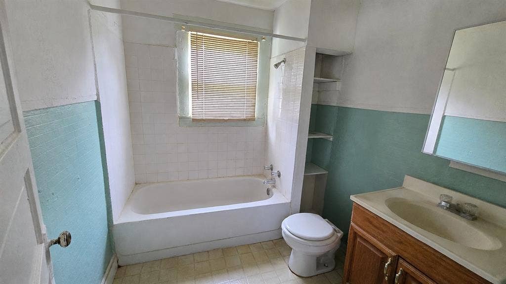 922 Hollywood Avenue, Dallas, TX 75208 Bathroom featuring a tub-shower combination with tile surround, built-in recessed shelving, a vanity with an integrated sink, and a wall-mounted mirror