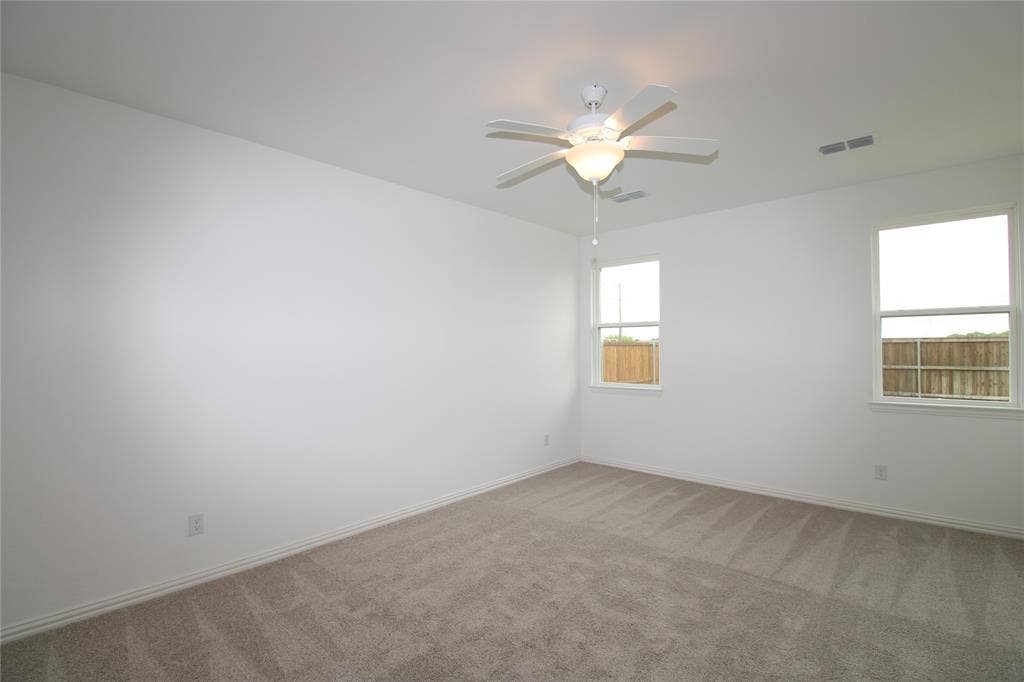 2603 Swallowtail Street, Melissa, TX 75454 Interior room featuring neutral wall paint, wall-to-wall carpeting, two multi-pane windows, and a central ceiling fan with integrated lighting