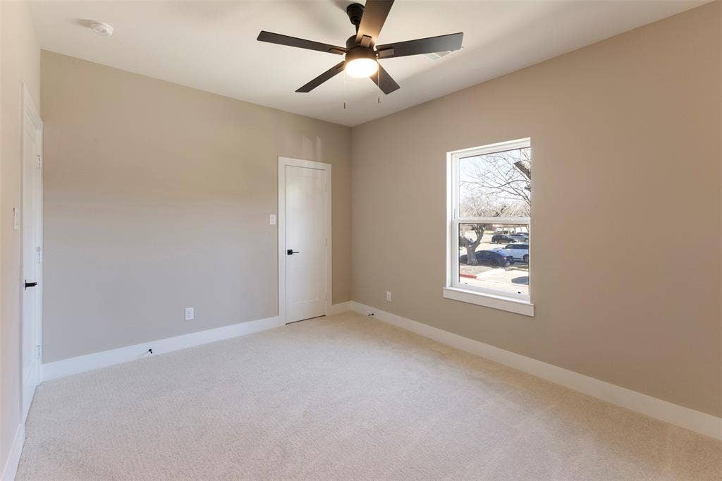 2390 Usman Drive, Irving, TX 75062 Neutral-toned interior featuring wall-to-wall carpeting, a multi-blade ceiling fan with integrated lighting, and a single-hung window with a wooden sill
