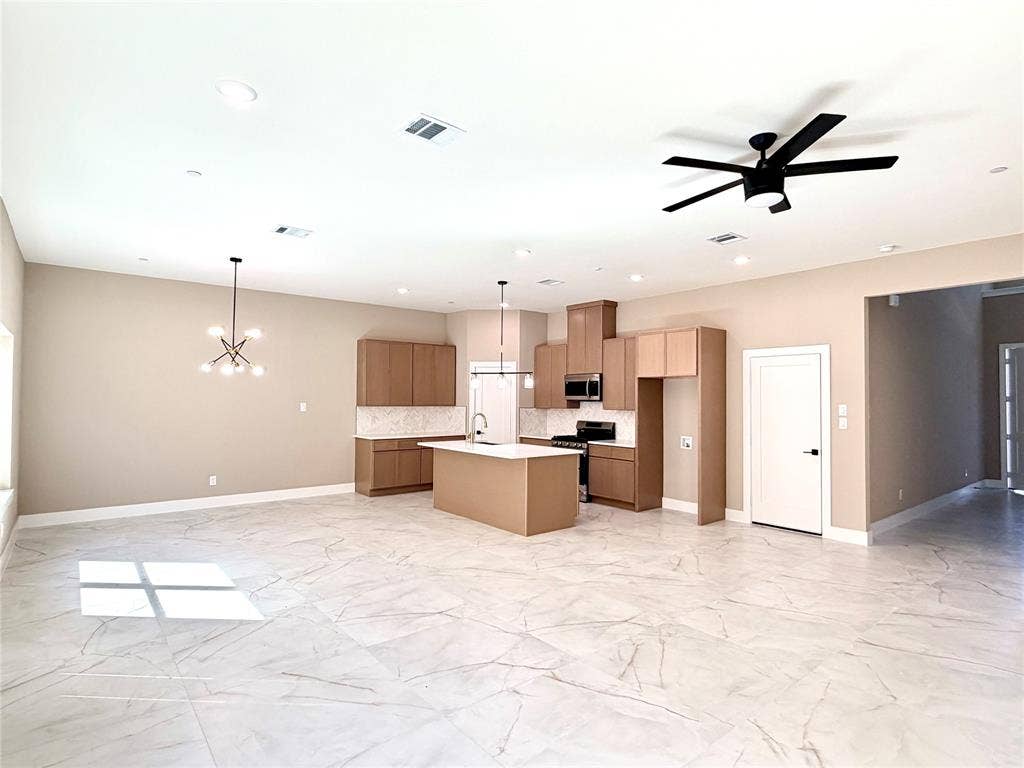 2390 Usman Drive, Irving, TX 75062 Open concept kitchen featuring flat-panel cabinetry, a central island with a solid surface countertop, stone-finish tile flooring, recessed lighting, and a modern multi-light chandelier