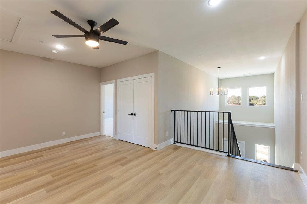 2390 Usman Drive, Irving, TX 75062 Open-concept space featuring light wood-finish flooring, a contemporary matte black ceiling fan, double-door closet, metal baluster railing, and a tiered chandelier