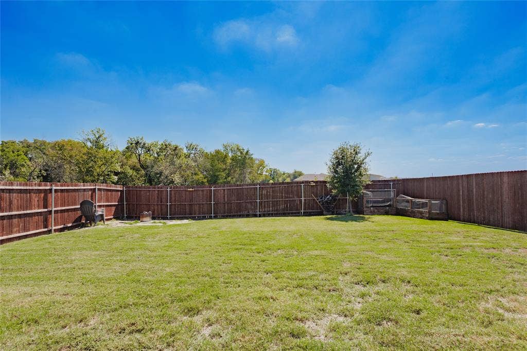 610 Overlook Point, Lavon, TX 75166 Spacious backyard featuring a manicured lawn, full-perimeter wood privacy fencing, and mature trees
