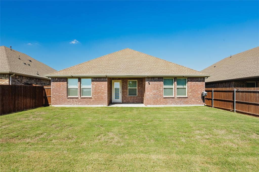 610 Overlook Point, Lavon, TX 75166 Brick exterior, hip roof, and rear lawn enclosed by wood privacy fencing