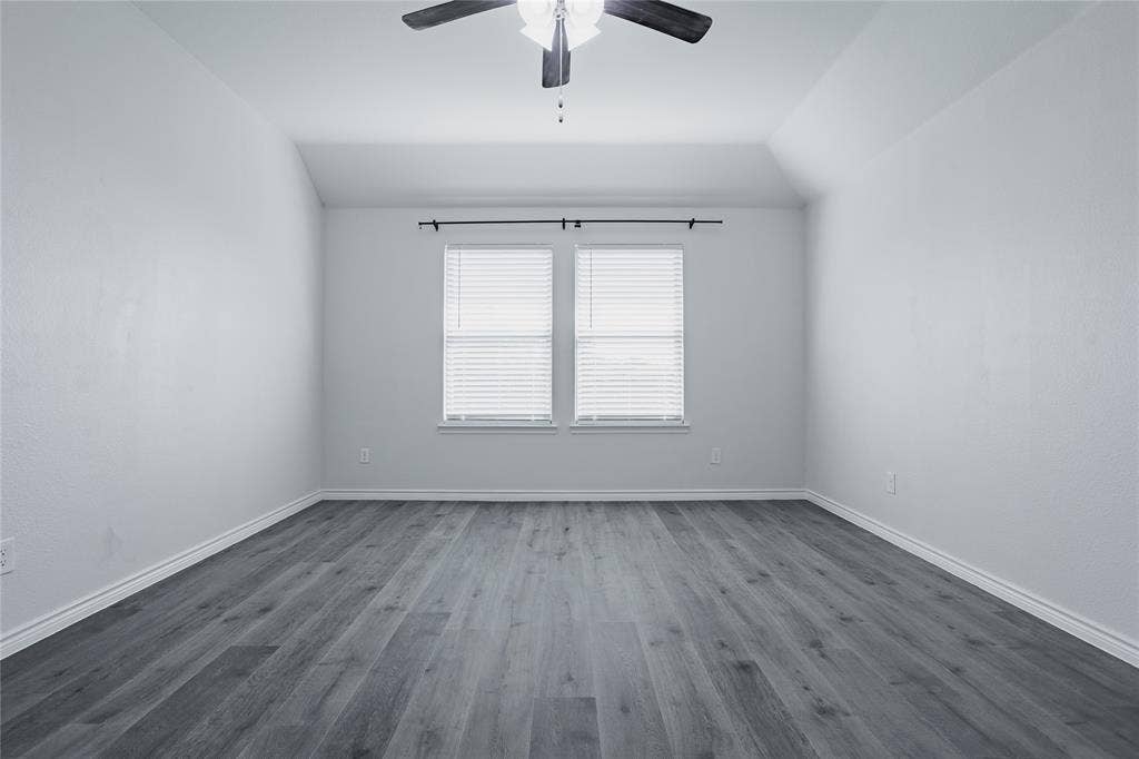 610 Overlook Point, Lavon, TX 75166 Vaulted ceiling with a centrally mounted ceiling fan, neutral wall finishes, wood-finish flooring, and dual windows featuring adjustable blinds