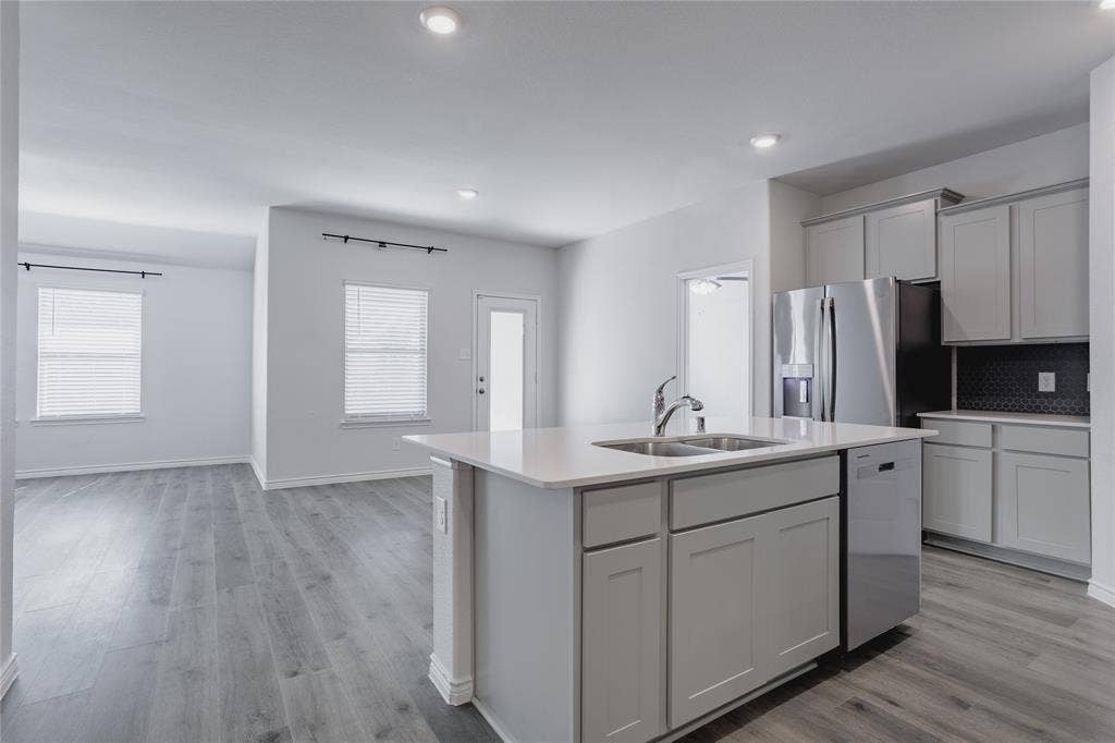610 Overlook Point, Lavon, TX 75166 Kitchen featuring a central island with a quartz countertop, stainless steel appliances, grey cabinetry, and wood-finish flooring