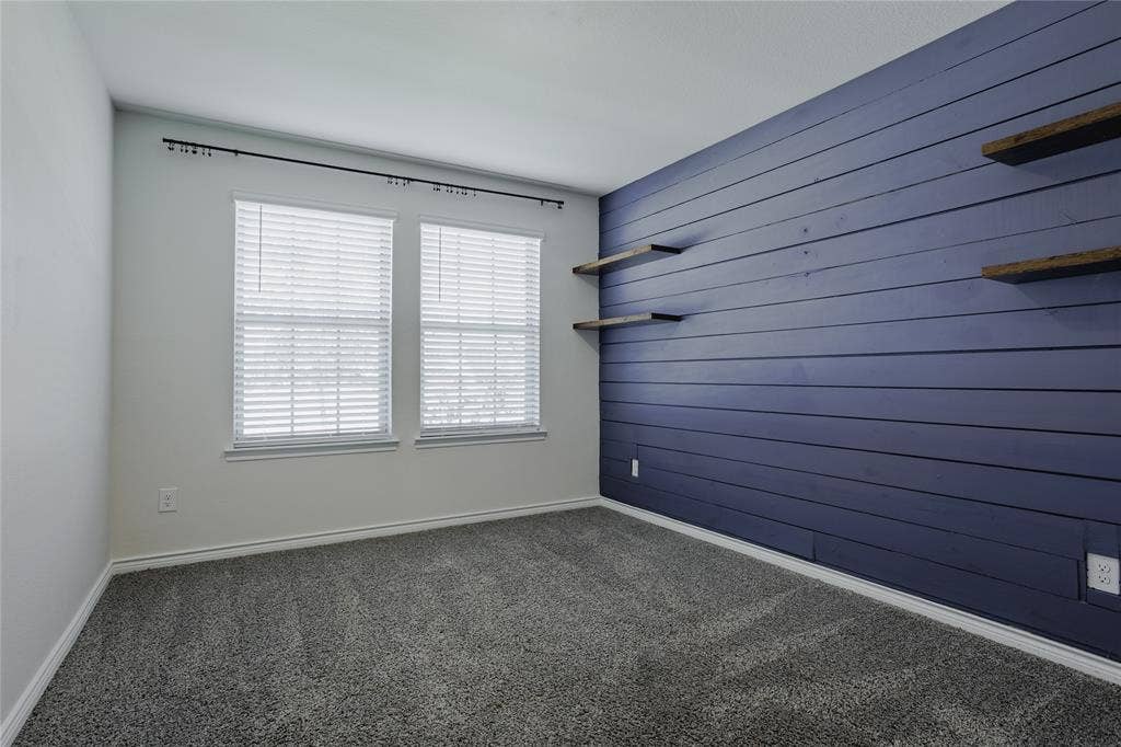 610 Overlook Point, Lavon, TX 75166 Room featuring blue horizontal shiplap accent wall, built-in floating wood-finish shelving, carpeted flooring, and dual windows with fitted blinds