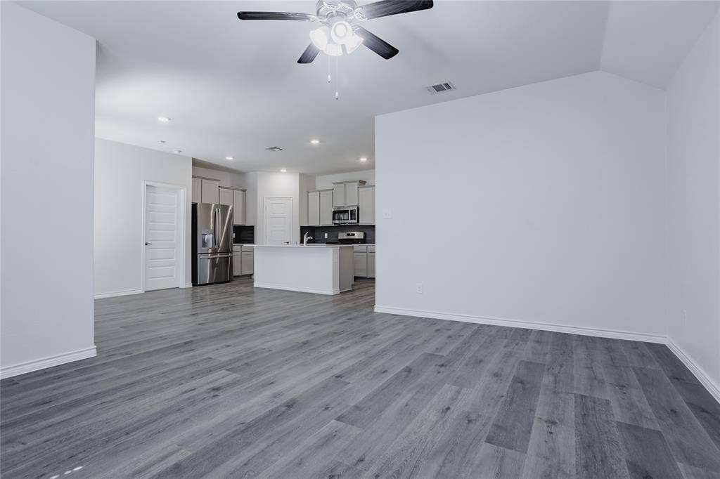 610 Overlook Point, Lavon, TX 75166 Open-concept interior featuring wood-finish flooring, vaulted ceilings, a kitchen island with stone-surface countertop, recessed lighting, and a ceiling fan with integrated lighting