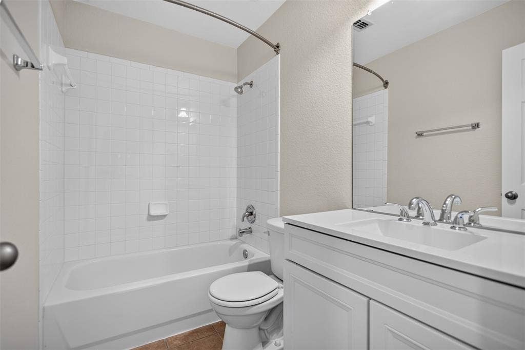 2691 Eganridge Lane, Rockwall, TX 75087 Bathroom featuring a white vanity with a composite countertop, an integrated sink with polished metal fixtures, a large wall-mounted mirror, and a bathtub with a white tile surround