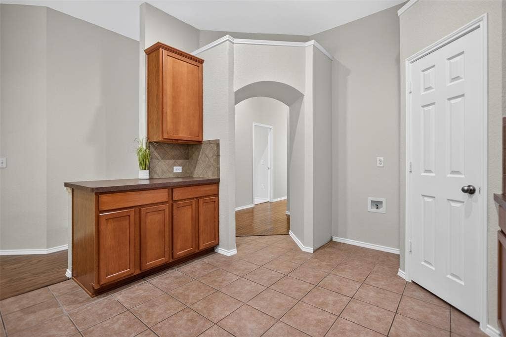 2691 Eganridge Lane, Rockwall, TX 75087 Built-in wood cabinetry with a countertop, tiled backsplash, arched architectural detailing, and tile flooring