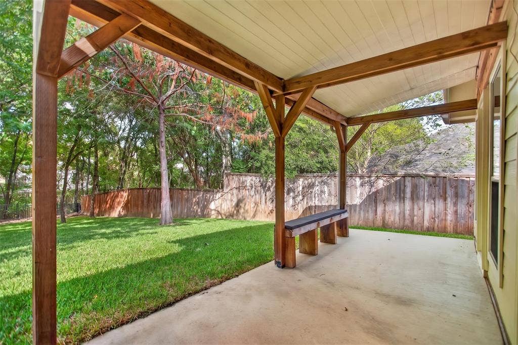 2691 Eganridge Lane, Rockwall, TX 75087 Covered patio featuring a wood-frame structure, built-in timber seating, a concrete floor, and an exterior wood privacy fence enclosing a grass lawn