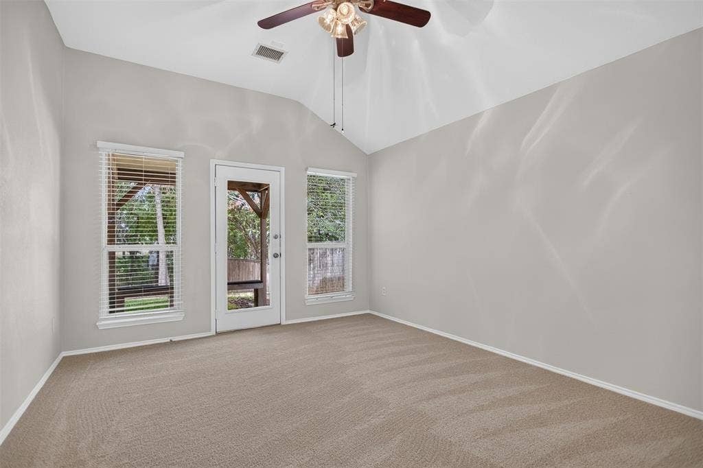 2691 Eganridge Lane, Rockwall, TX 75087 Vaulted ceiling featuring a central lighted ceiling fan, neutral wall tones, wall-to-wall carpeting, and an exterior door flanked by dual windows