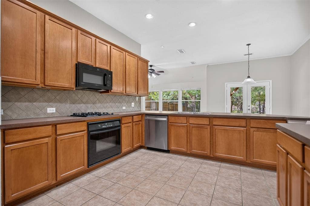2691 Eganridge Lane, Rockwall, TX 75087 Kitchen featuring medium-toned wood cabinetry, stone-style tile backsplash, stainless steel dishwasher, built-in black gas cooktop and oven, and recessed lighting