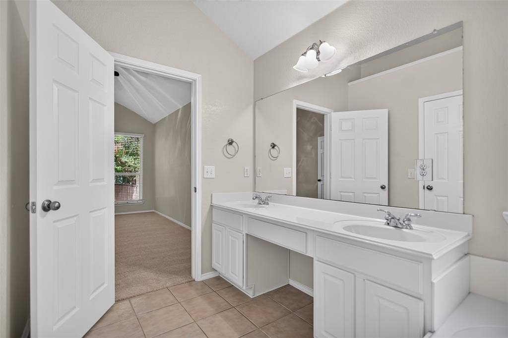 2691 Eganridge Lane, Rockwall, TX 75087 Dual-sink vanity with white cabinetry, solid-surface countertop, full-width wall mirror, and ceramic tile flooring