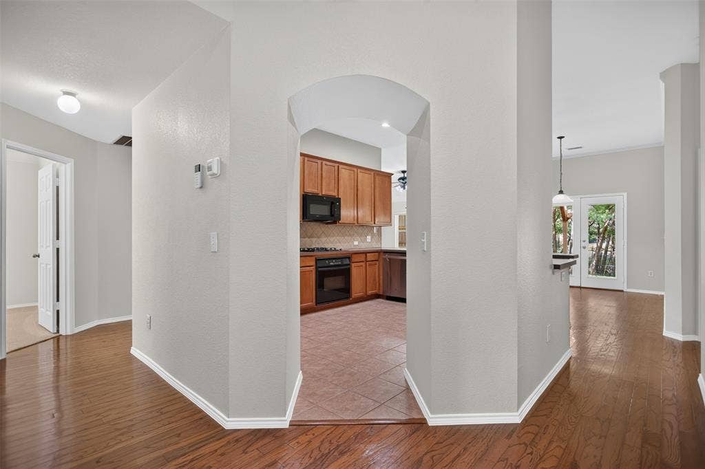 2691 Eganridge Lane, Rockwall, TX 75087 Interior featuring wood-finish flooring, an arched entryway, tile flooring in the kitchen, built-in cabinetry, and a glass-paned exterior door