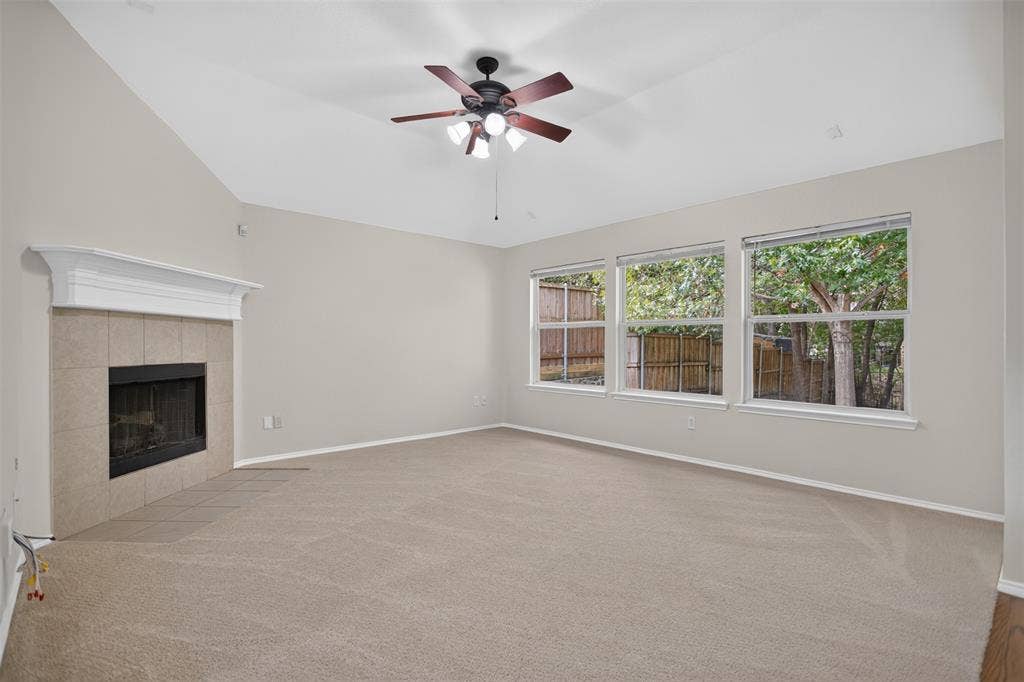 2691 Eganridge Lane, Rockwall, TX 75087 Vaulted ceilings, neutral carpeting, a fireplace with a mantel and tile surround, and a ceiling fan with integrated lighting