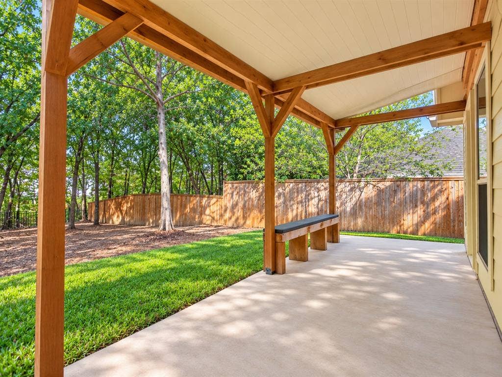 2691 Eganridge Lane, Rockwall, TX 75087 Covered patio featuring a timber-frame pergola, concrete flooring, built-in wooden bench, and backyard with grass lawn and wood fencing